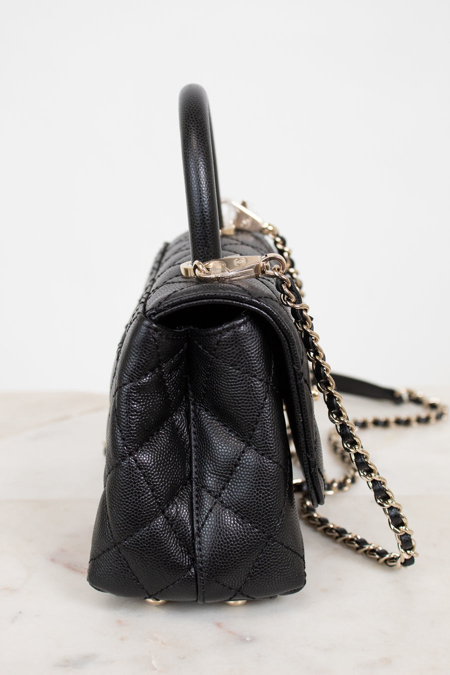 Black quilted handbag with a chain strap on a light background
