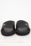 Pair of black slides with Chanel logo on a white background