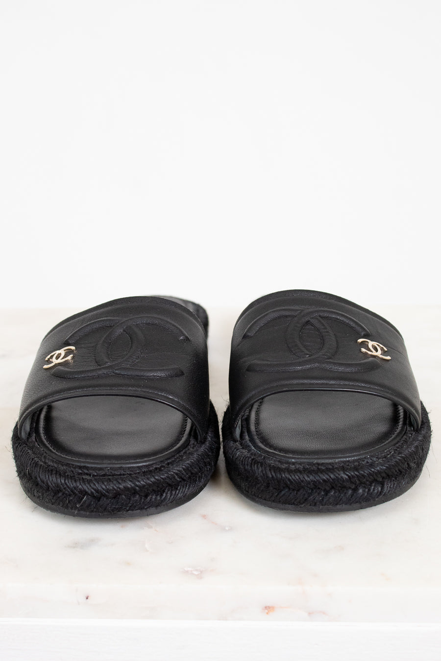 Pair of black slides with Chanel logo on a white background