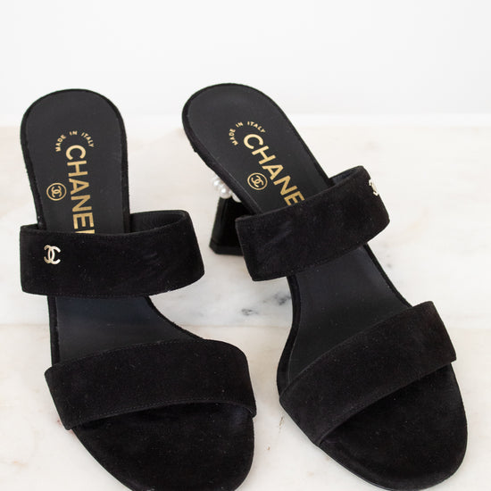 Black Chanel sandals on a white marble surface