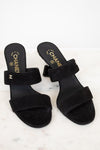 Black Chanel sandals on a white marble surface
