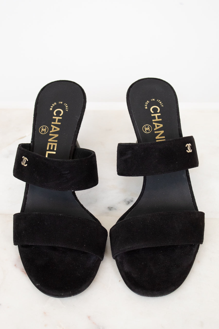 Pair of black Chanel sandals on a white background