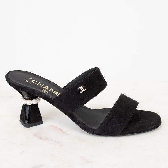 Black sandal with a high heel and pearl detail on a white background