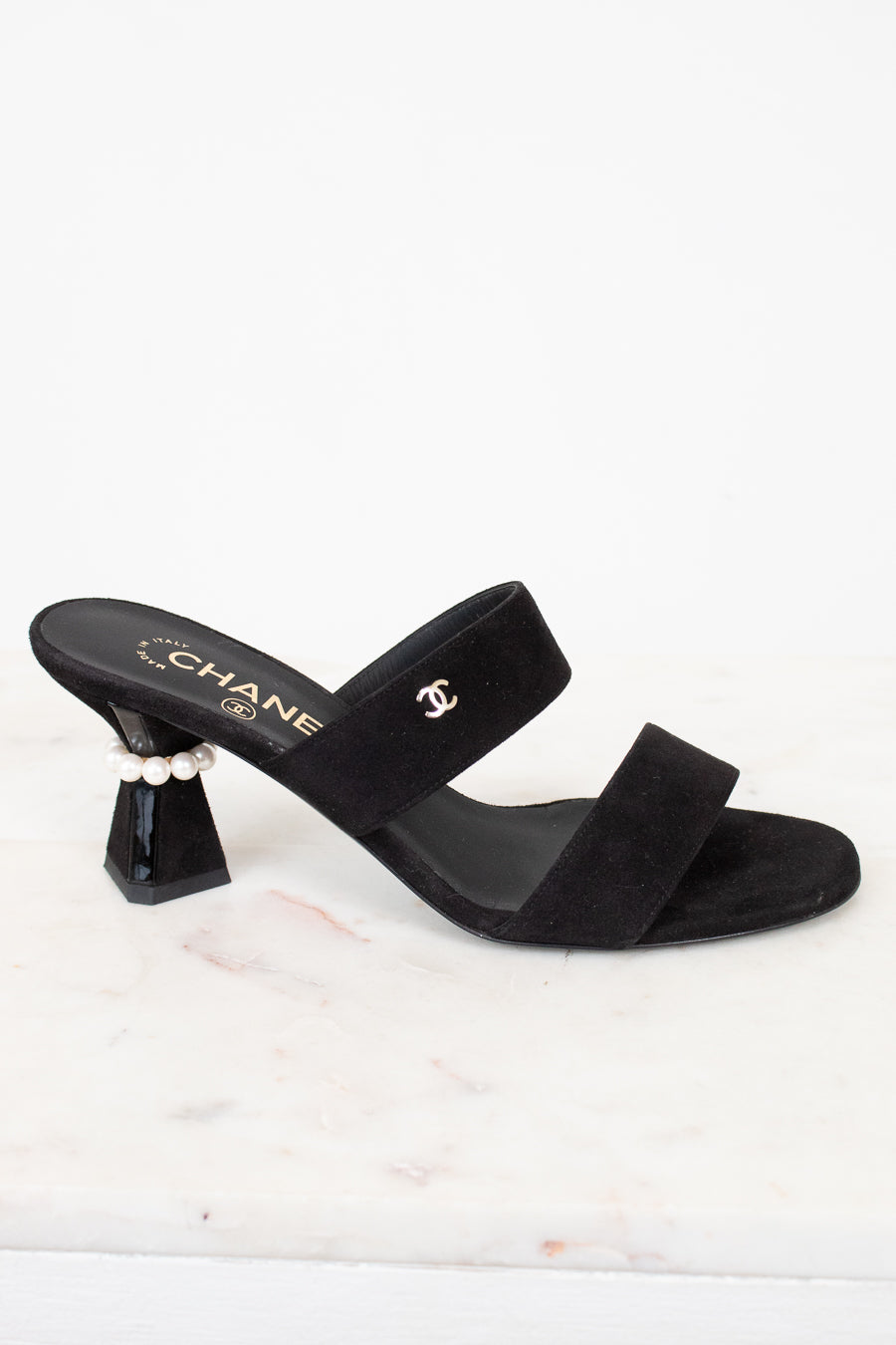 Black sandal with a high heel and pearl detail on a white background