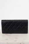 A black quilted leather wallet with a diamond pattern, resting on a white marble surface against a white background.