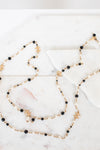 Long necklace with black and faux pearl beads on a marble surface