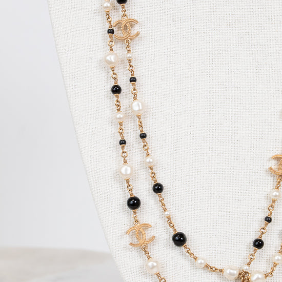 Chanel necklace with black and faux pearl beads on a white background