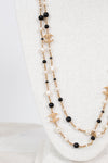 Chanel necklace with black and faux pearl beads on a white background