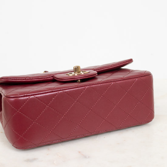 A quilted red leather handbag with gold-tone hardware, resting on a white marble surface against a white background.