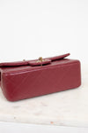 A quilted red leather handbag with gold-tone hardware, resting on a white marble surface against a white background.