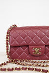 A close-up of a quilted burgundy leather handbag with a gold-tone interlocking CC clasp and a matching burgundy and gold chain strap, set against a clean white background.