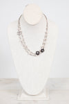 A double-strand silver-toned necklace displayed on a white fabric jewelry bust. The necklace features small silver beads, a silver chain with clear rhinestones, and two black floral cluster charms with clear rhinestones.