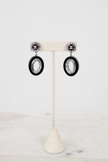 Pair of earrings on a white stand with a light background