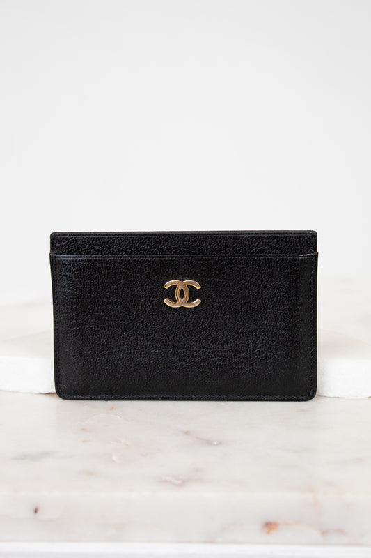 Black leather wallet with gold CC logo on a white marble surface