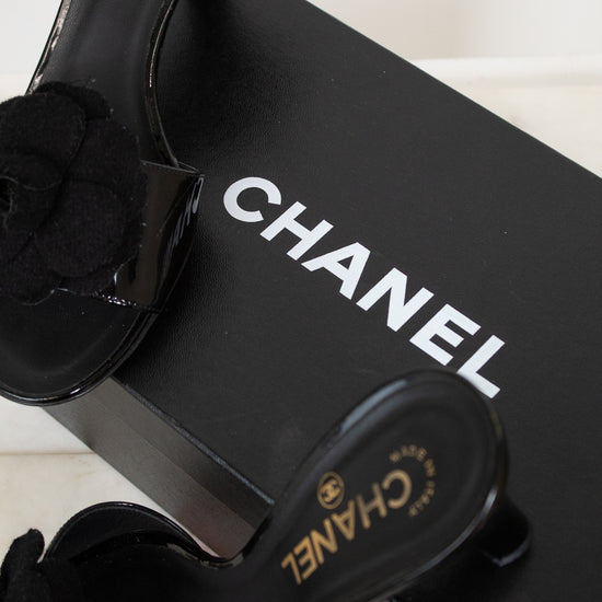 Black Chanel kitten heels with a black flower on a Chanel box.