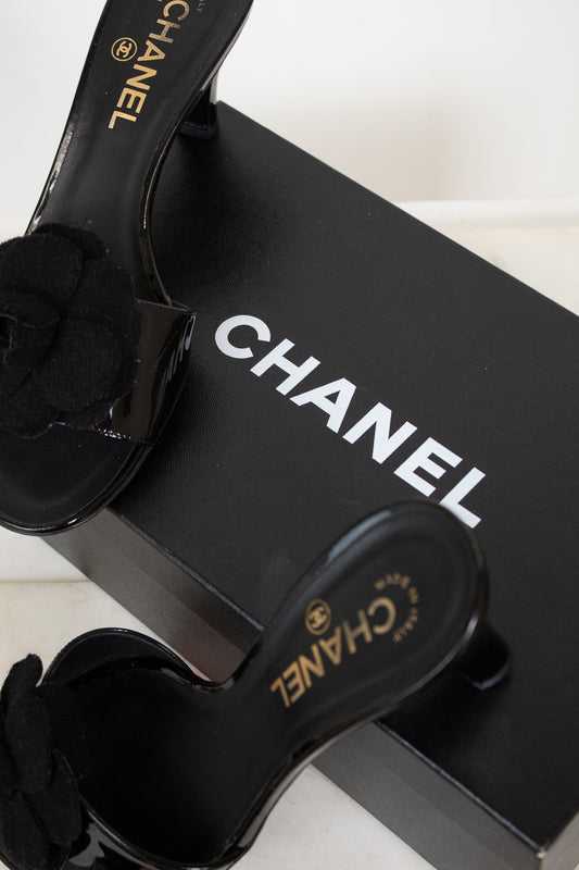 Black Chanel kitten heels with a black flower on a Chanel box.