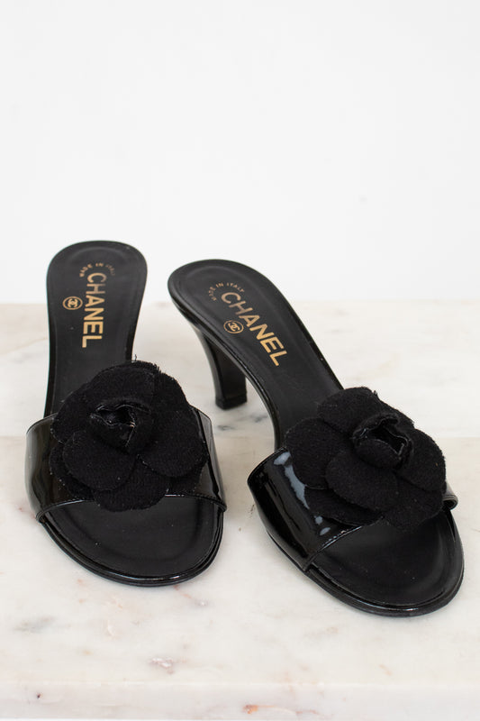 Black Chanel kitten heels with floral details on a marble surface