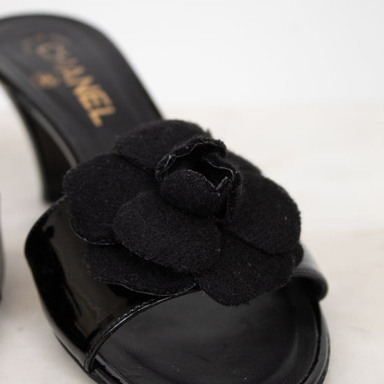 Black Chanel kitten heels with flower detail on a white background