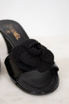 Black Chanel kitten heels with flower detail on a white background