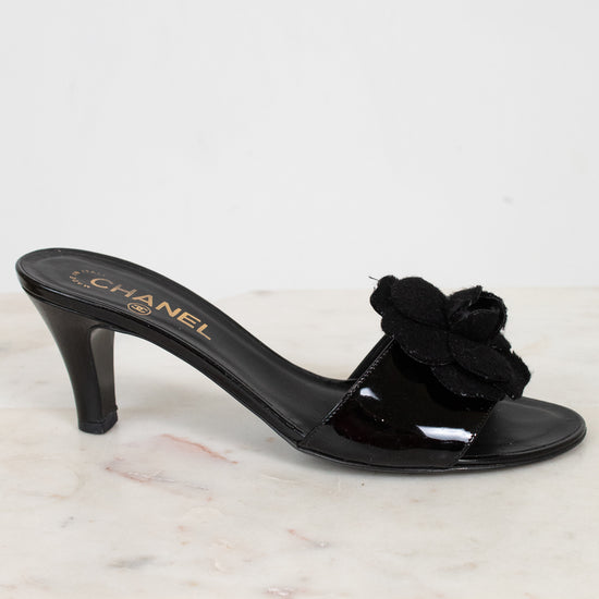 Black Chanel kitten heel with a flower detail on a white marble surface