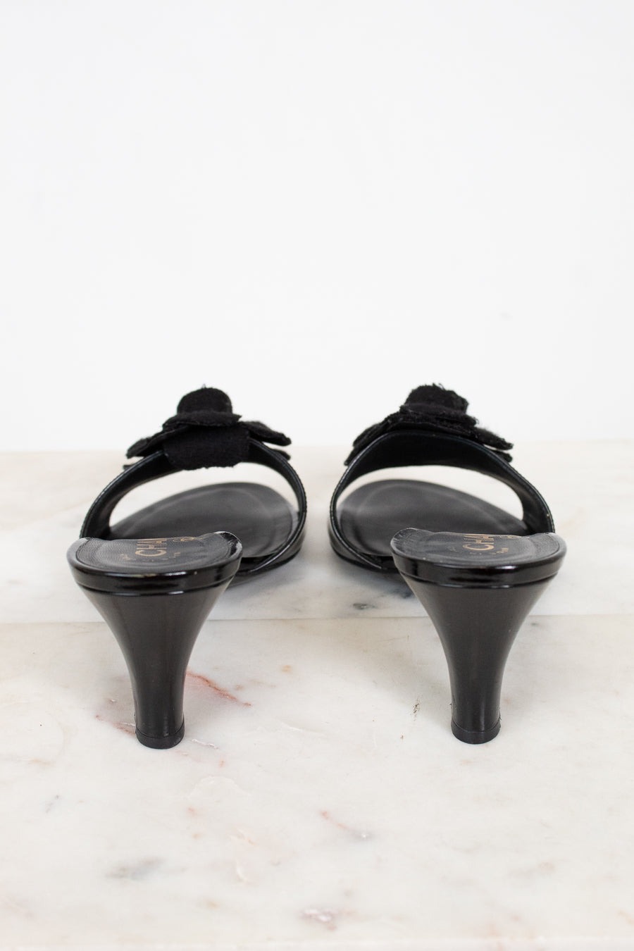 Pair of black kitten heels on a light marble surface
