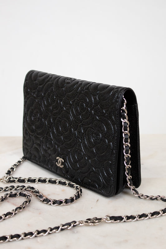 Black floral quilted handbag with chain strap on a light background