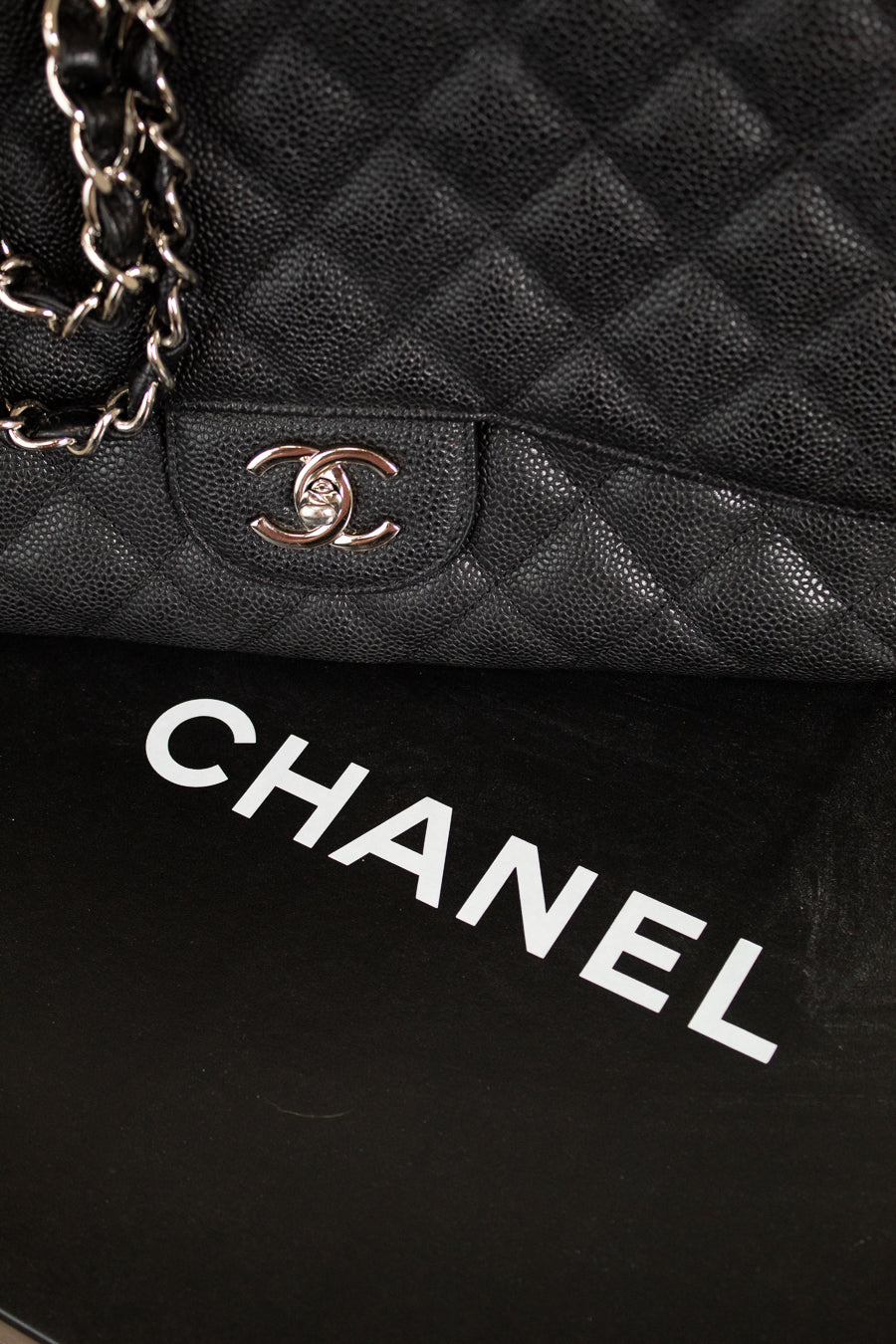 Close-up of a black quilted Chanel handbag with the brand logo.