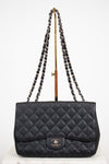 Black quilted handbag with chain strap on a white background