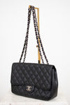 Black quilted handbag with chain strap on a white background