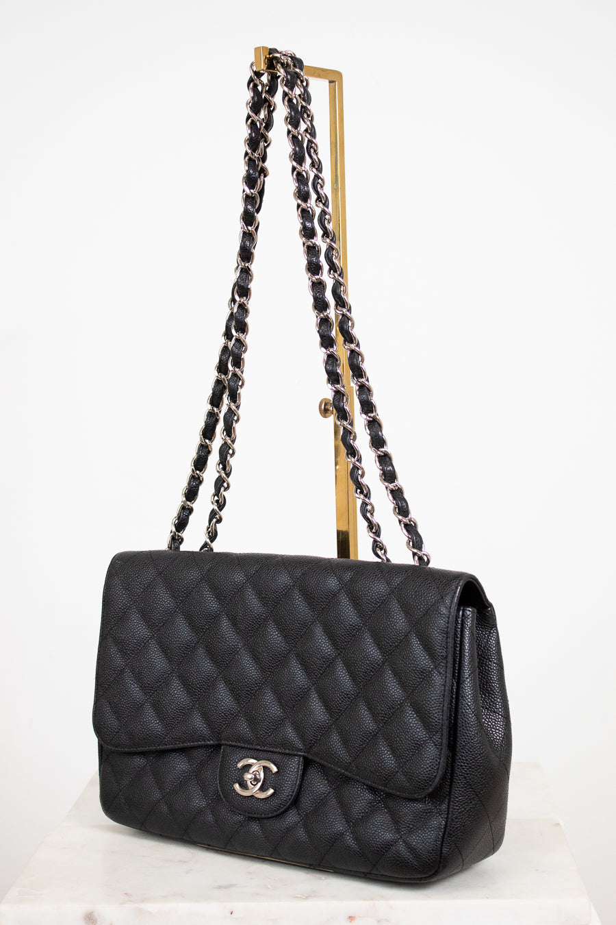 Black quilted handbag with chain strap on a white background