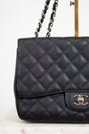 Black quilted Chanel handbag on a white background