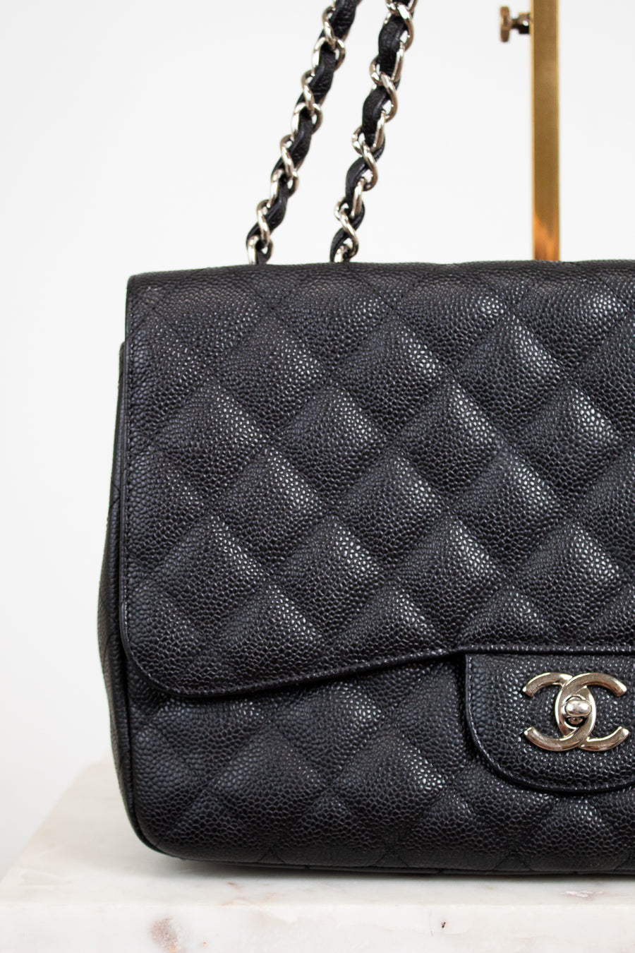 Black quilted Chanel handbag on a white background