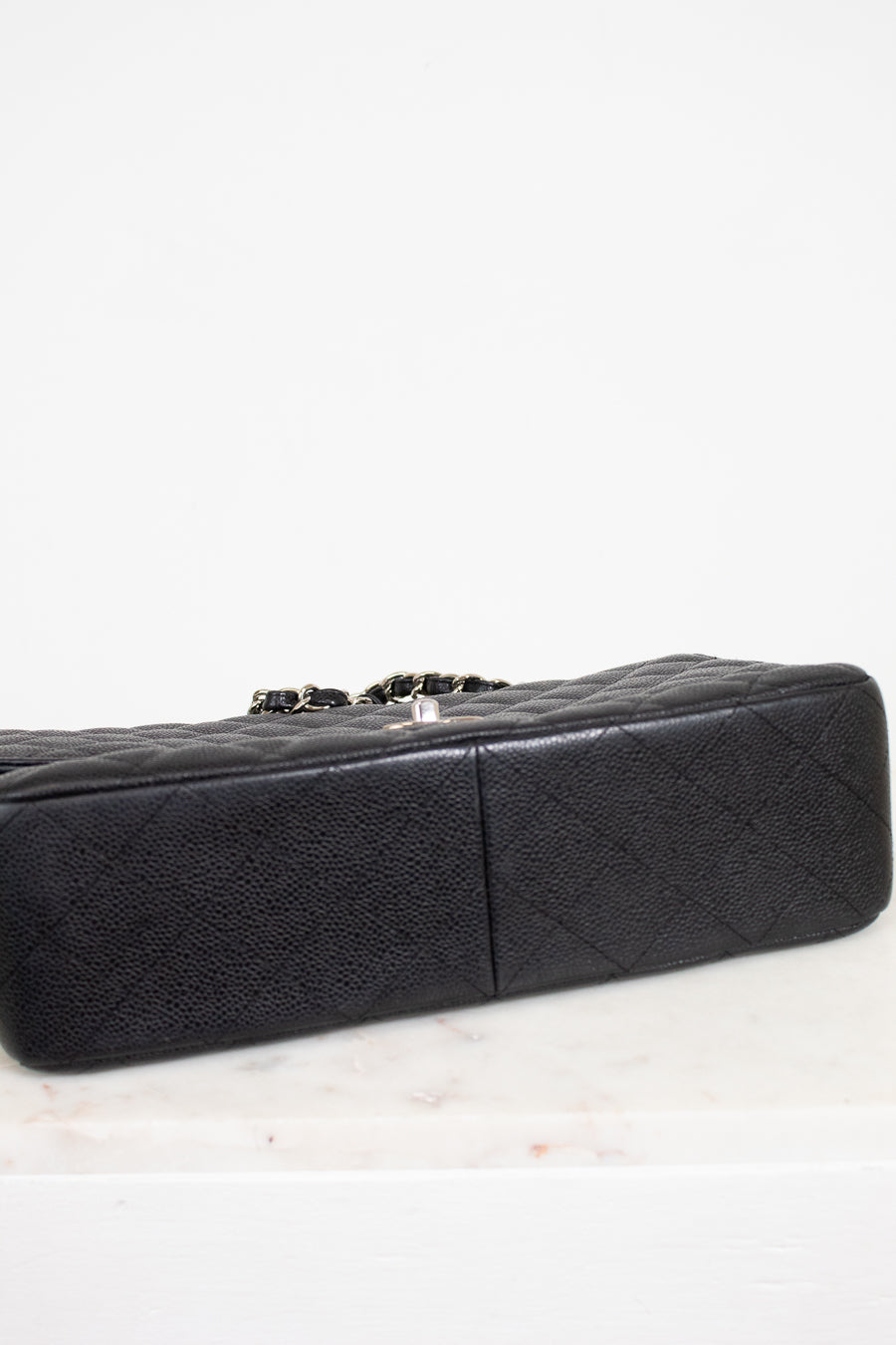 Black quilted handbag on a light gray background