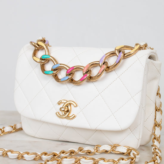 White quilted handbag with gold chain strap on a light gray background