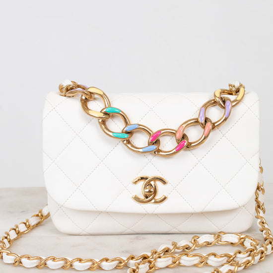 White quilted handbag with gold chain strap on a light background