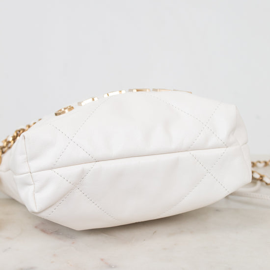 A white quilted leather shoulder bag with a gold chain strap, resting on a light marble surface against a white background.