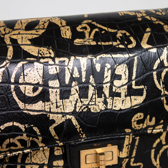 Black handbag with gold logo pattern on a light gray background