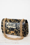 Black handbag with gold chain strap and graffiti-style text on a white background