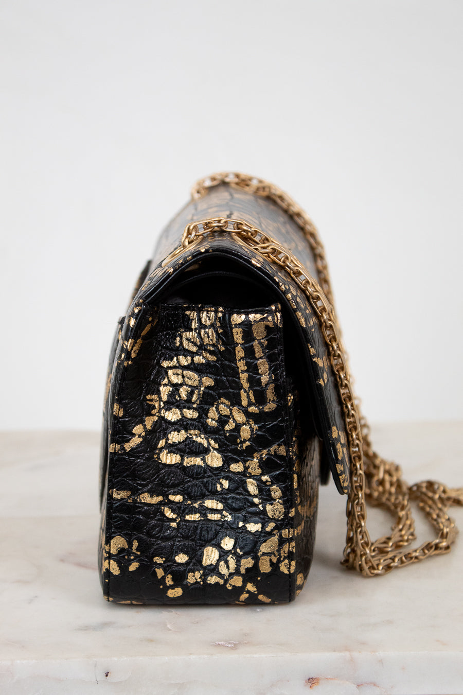 Black handbag with gold chain strap on a white background