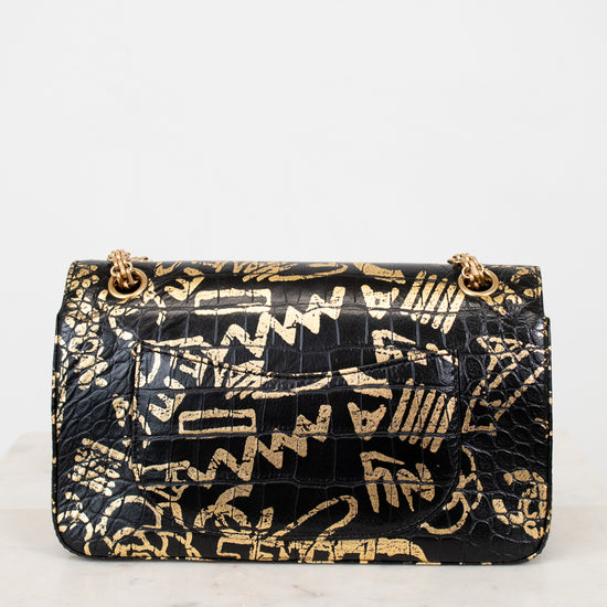 Black handbag with gold geometric pattern on a white background
