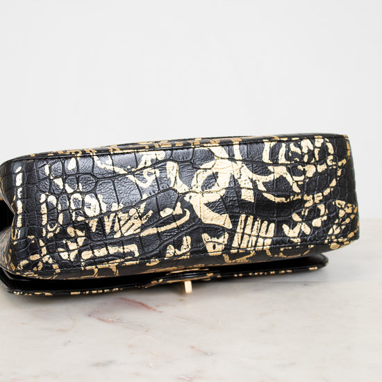 Black handbag with gold patterns on a white surface