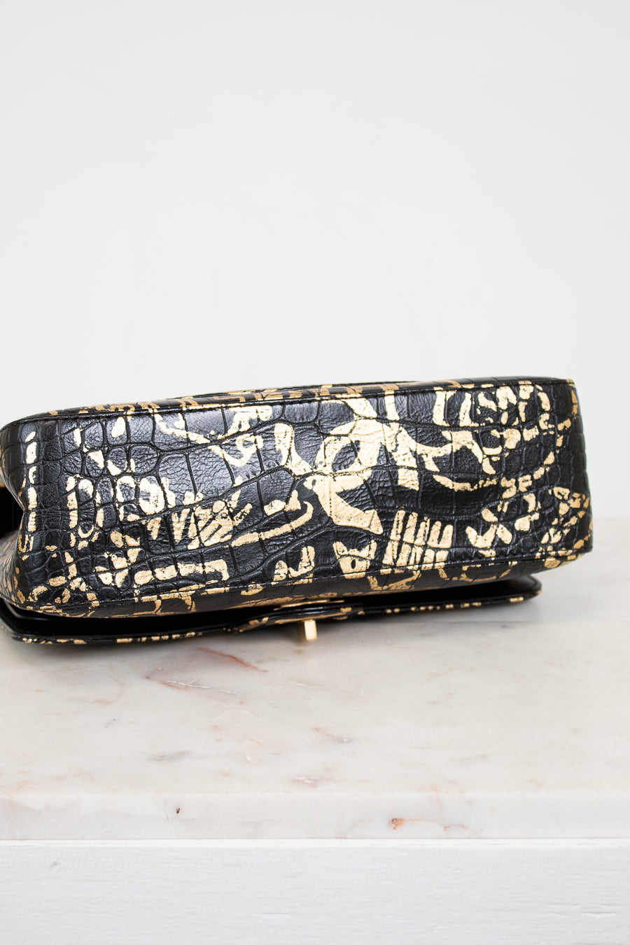 Black handbag with gold patterns on a white surface