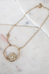Gold necklace with a floral pendant on a marble surface