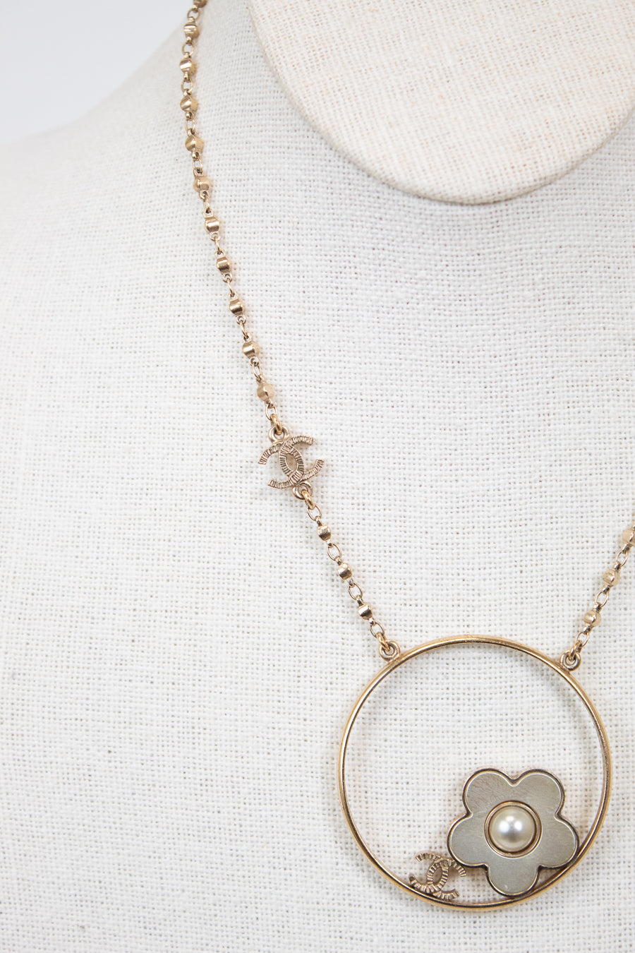 Necklace with a floral pendant and pearl on a light gray background