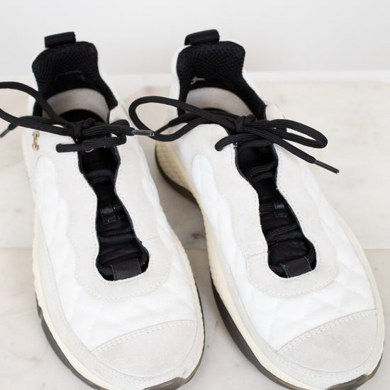 White sneakers with black laces on a light marble surface