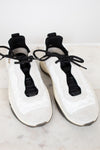 White sneakers with black laces on a light marble surface