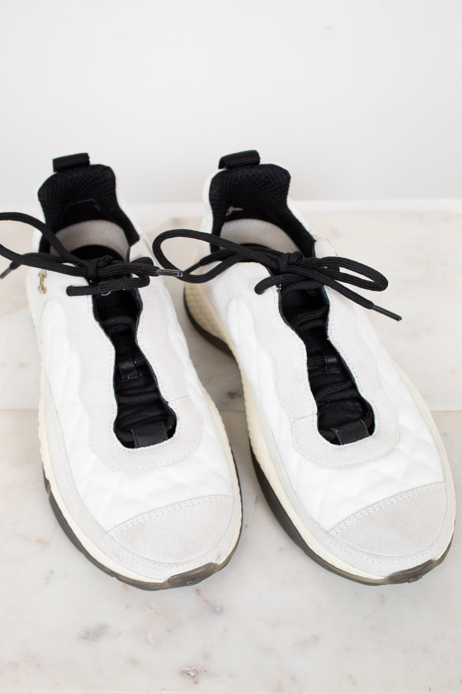 White sneakers with black laces on a light marble surface