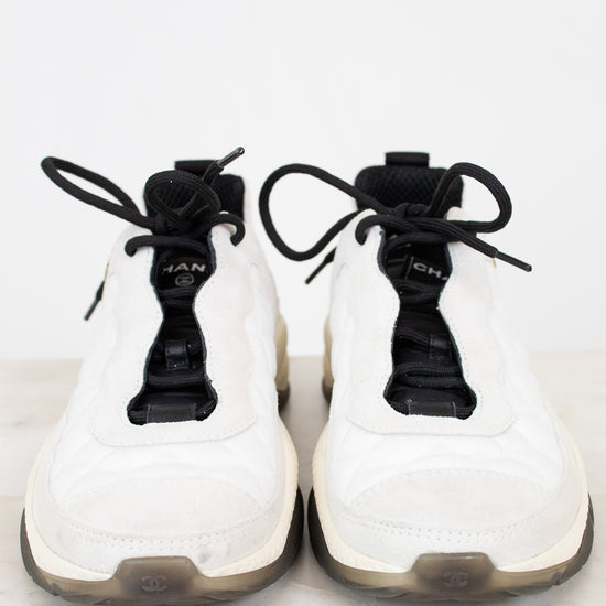 White sneakers with black laces on a white marble surface