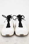 White sneakers with black laces on a white marble surface