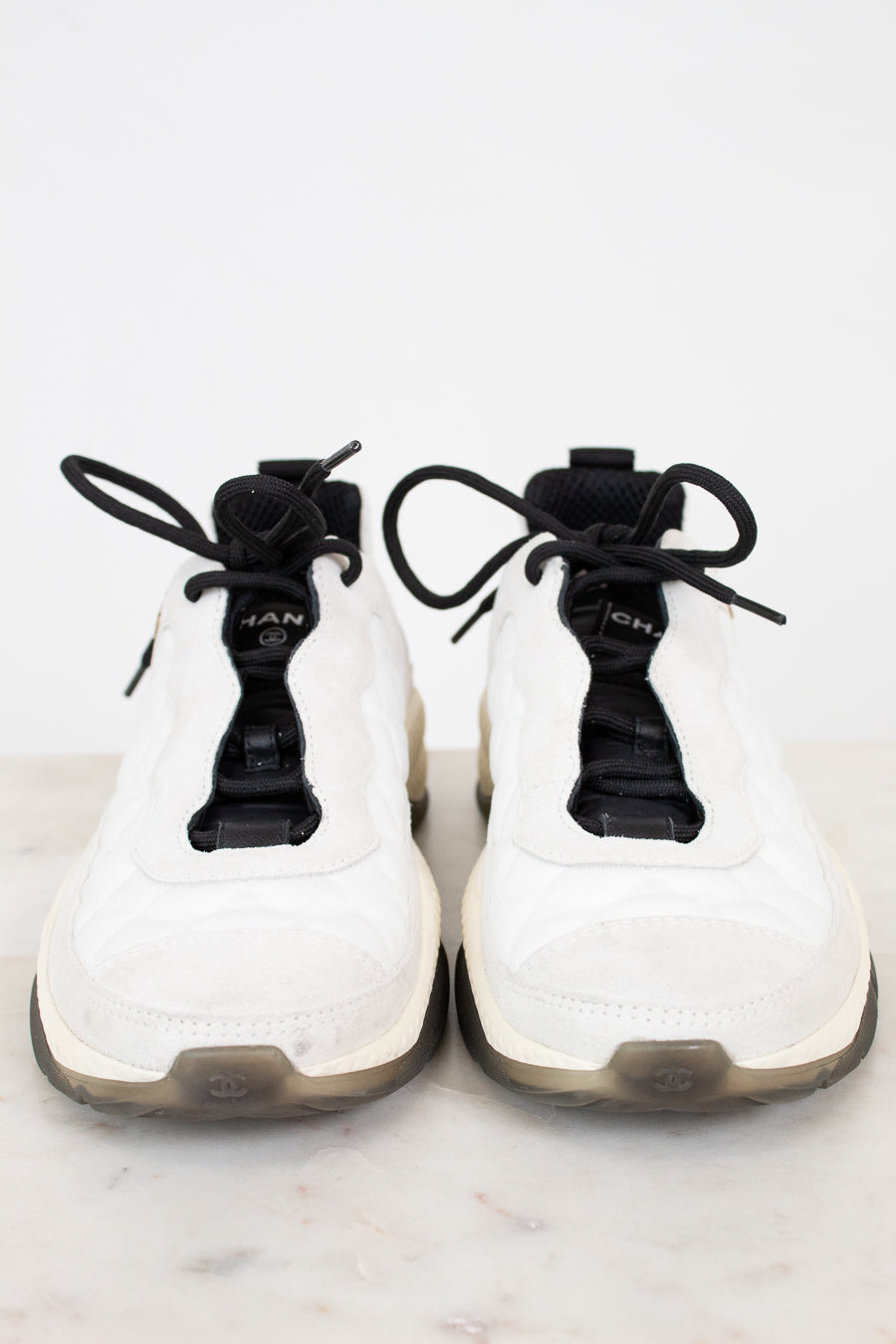 White sneakers with black laces on a white marble surface